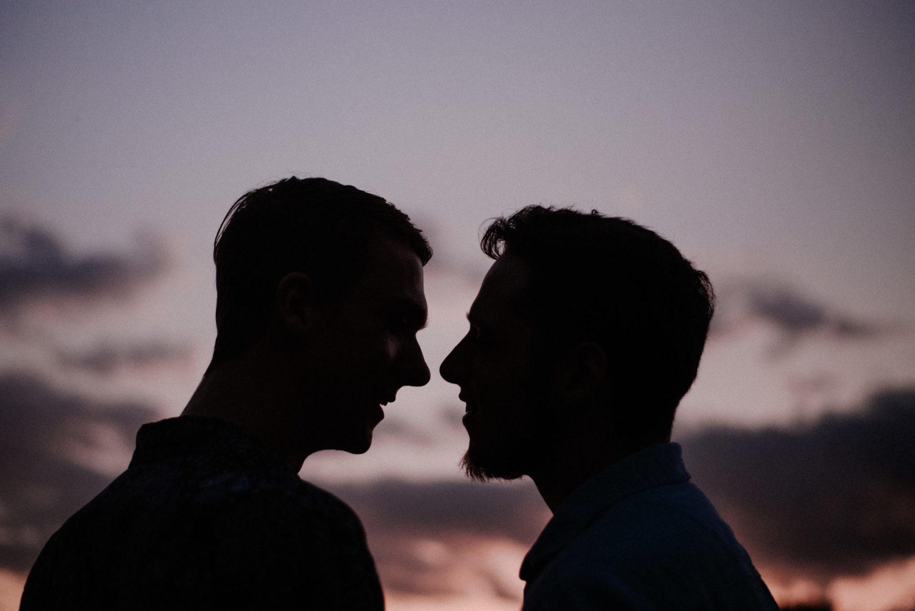 A romantic silhouette of a couple facing each other closely at sunset, capturing their intimate connection against the backdrop of a twilight sky.
