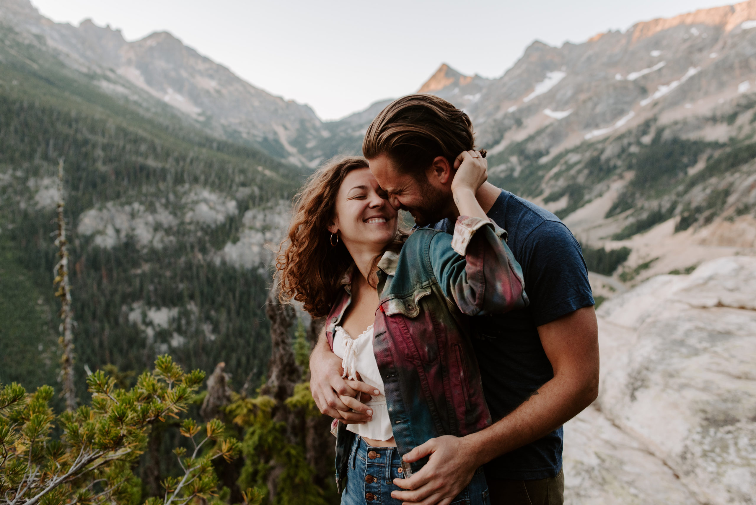 A couple embracing and smiling with a stunning mountain view in the background.