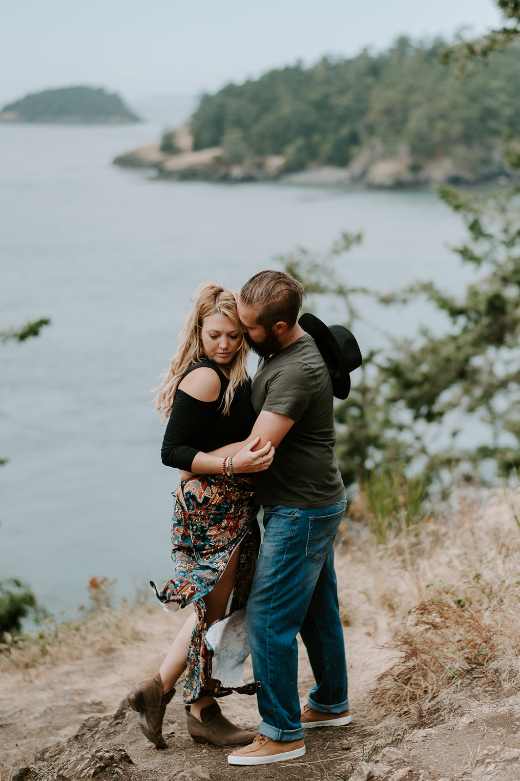 Couple embracing on a cliffside overlooking the water during their Deception Pass anniversary session.