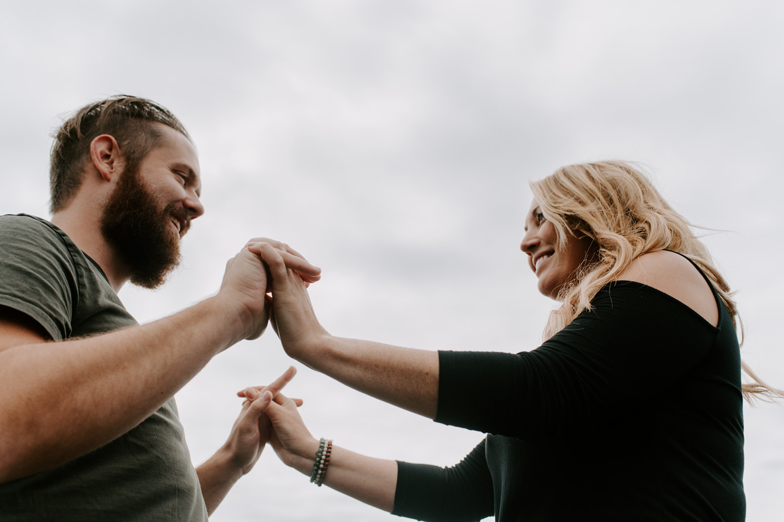 Playful moment as the couple holds hands and smiles at each other during their Deception Pass anniversary session.