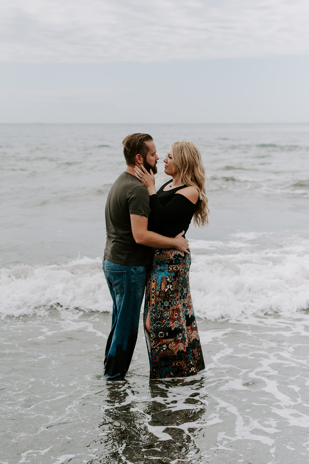 Couple embraces in the ocean, sharing an intimate moment during their Deception Pass anniversary session.