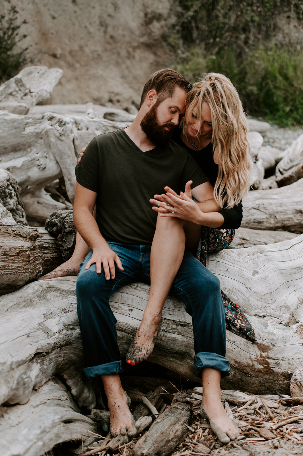 Couple sitting on driftwood, sharing an intimate moment during their Deception Pass anniversary session.