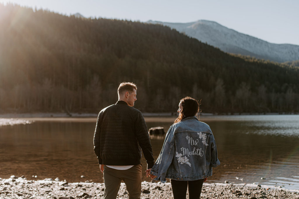 young couple at a lake hill side backing the camera and holding hands