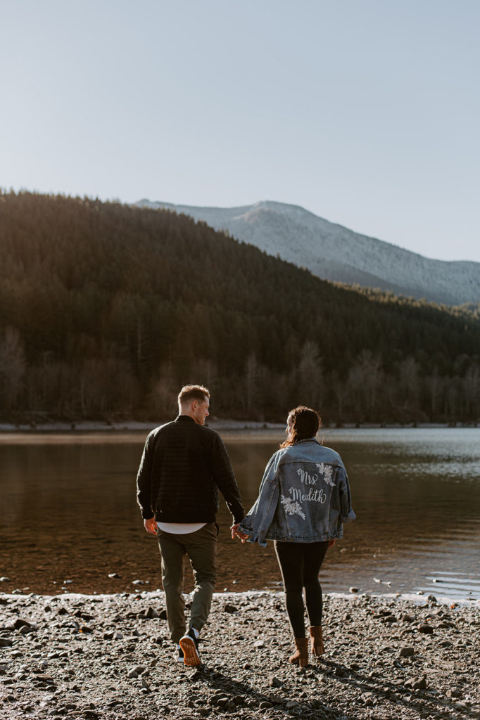 young couple at a lake hill side backing the camera and holding hands