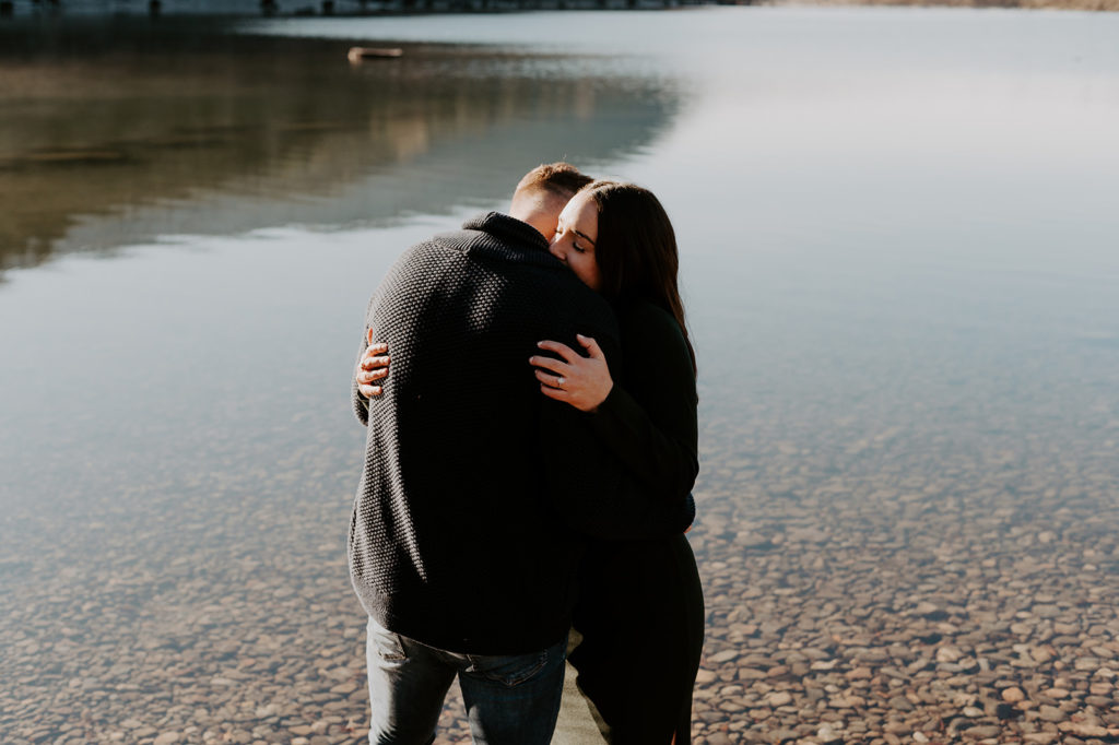 couple standing arm in arm near the lake making a romantic soft hug