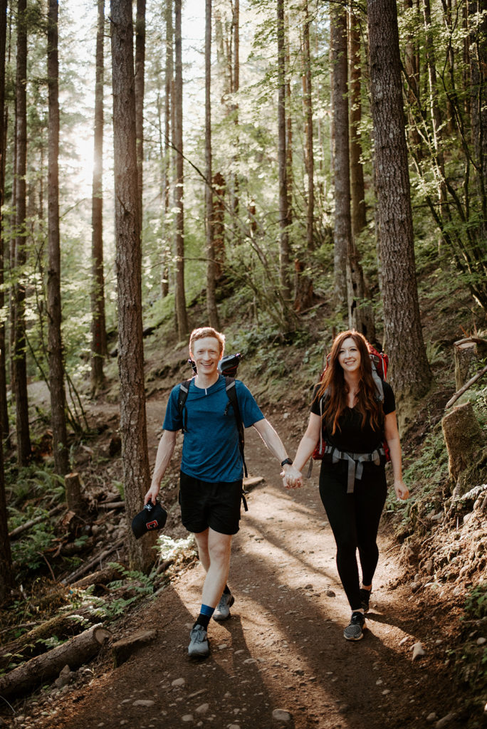 couple walking in the forest holding hands and facing the camera