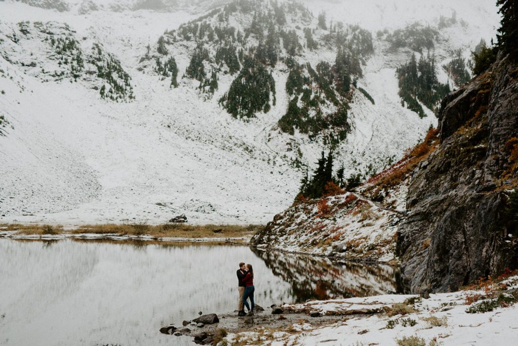 long shot of a couple standing together in between a large mountain area covered with snow