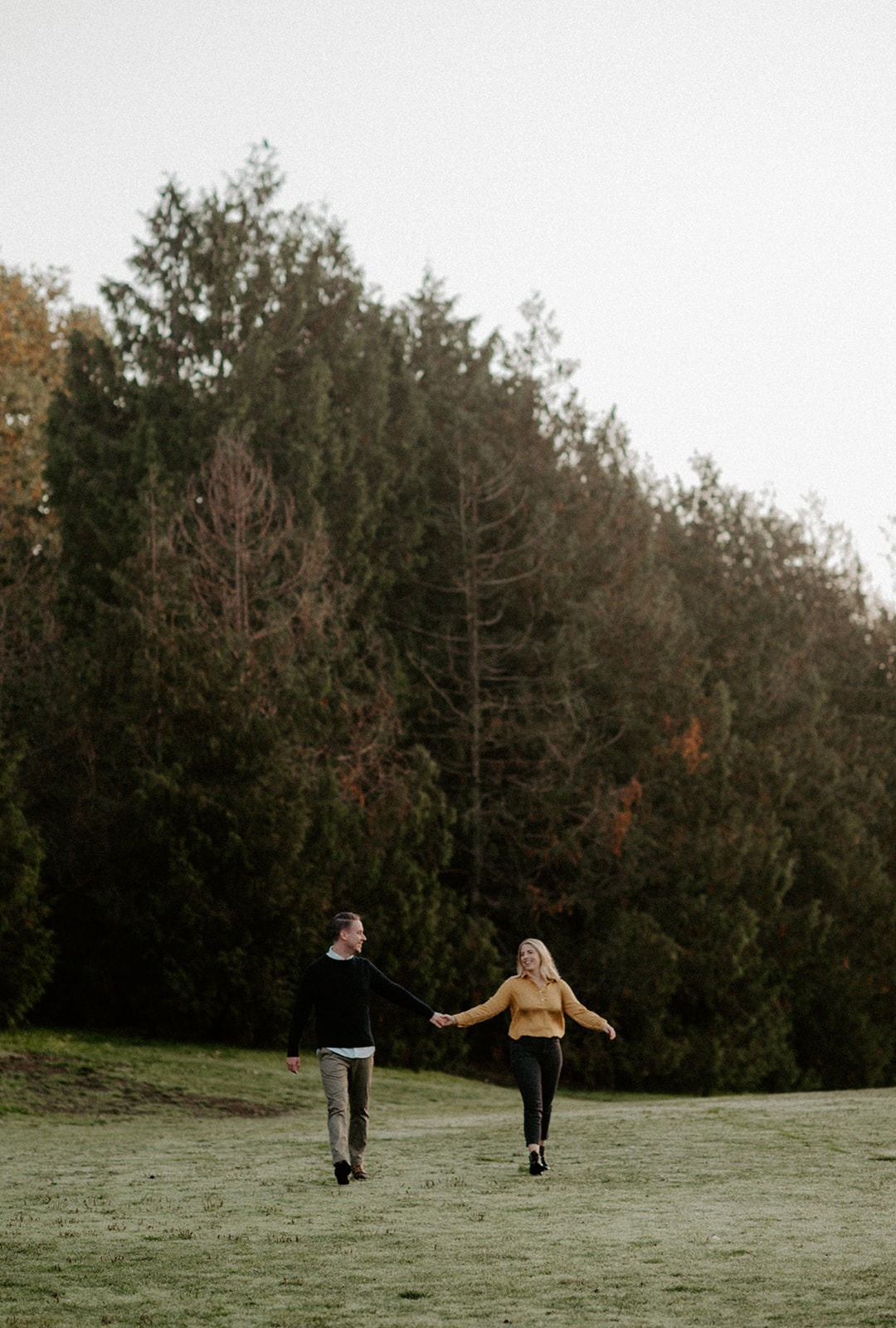 Couple running together across an open field during a Seattle engagement session