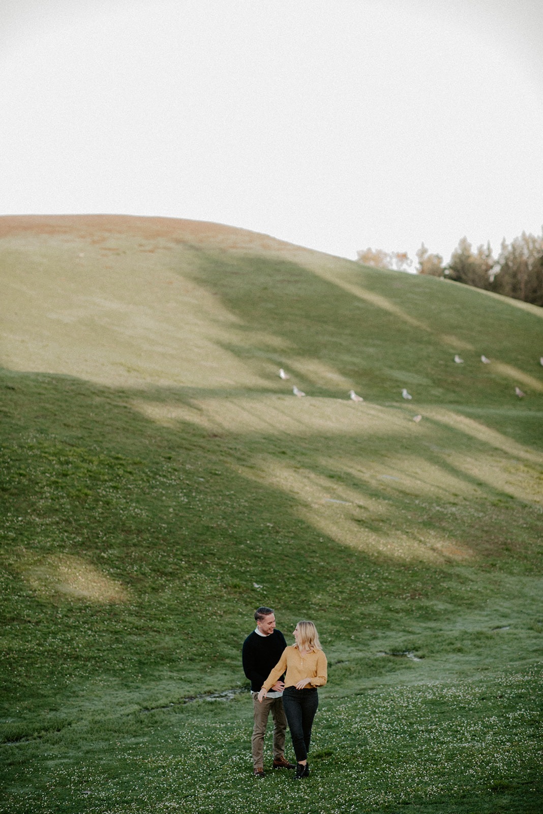 Couple walking down a grassy hill with skyline views during a Gas Works Park engagement session