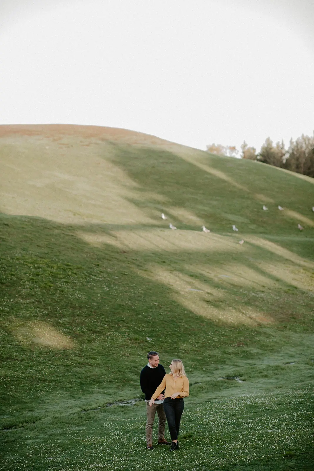 Couple walking down a grassy hill with skyline views during a Gas Works Park engagement session