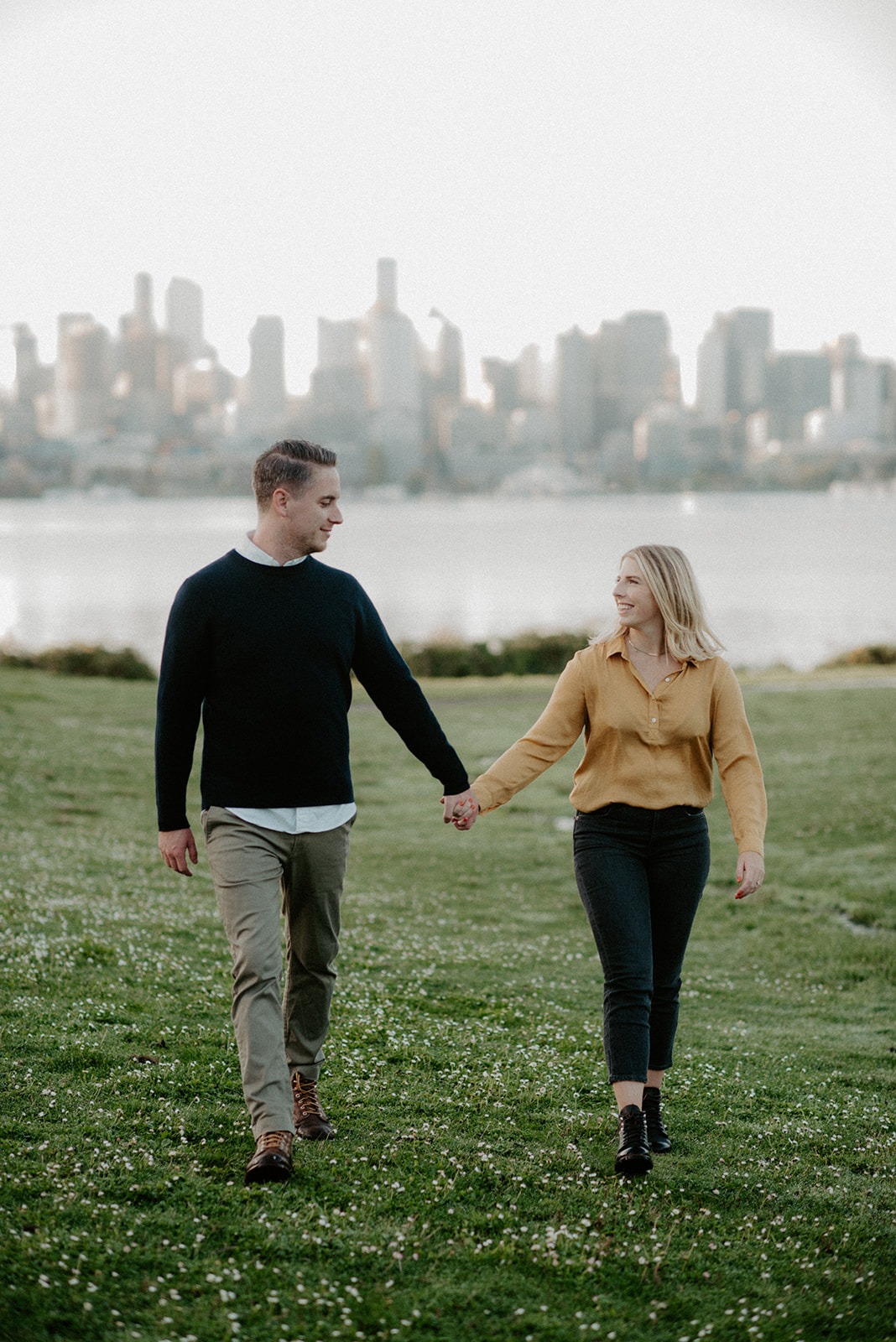 Couple holding hands and walking through the grassy fields at Gas Works Park engagement session
