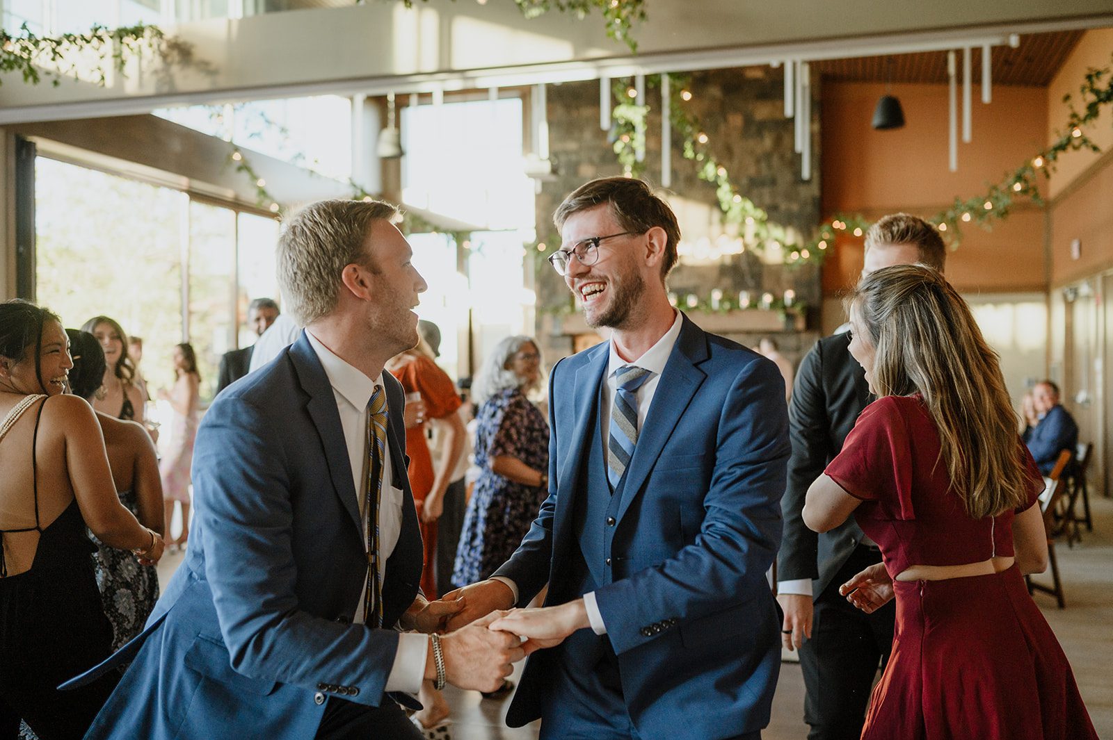 Two guests sharing a light-hearted, joyous dance at a wedding reception, surrounded by smiling friends and family, in a moment of pure celebration captured by Lindsey Paradiso Photography.