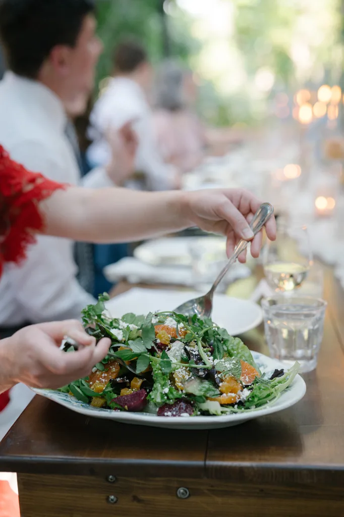 Guest serving a fresh, colorful farm-to-table salad at a wedding reception at The Corson Building, reflecting Seattle's commitment to locally sourced and elegantly served cuisine.