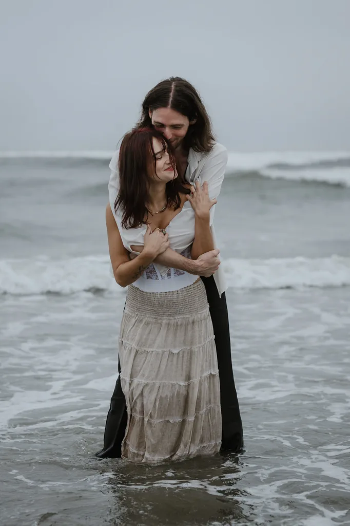 Engaged couple in a tender embrace by the ocean on the Oregon coast