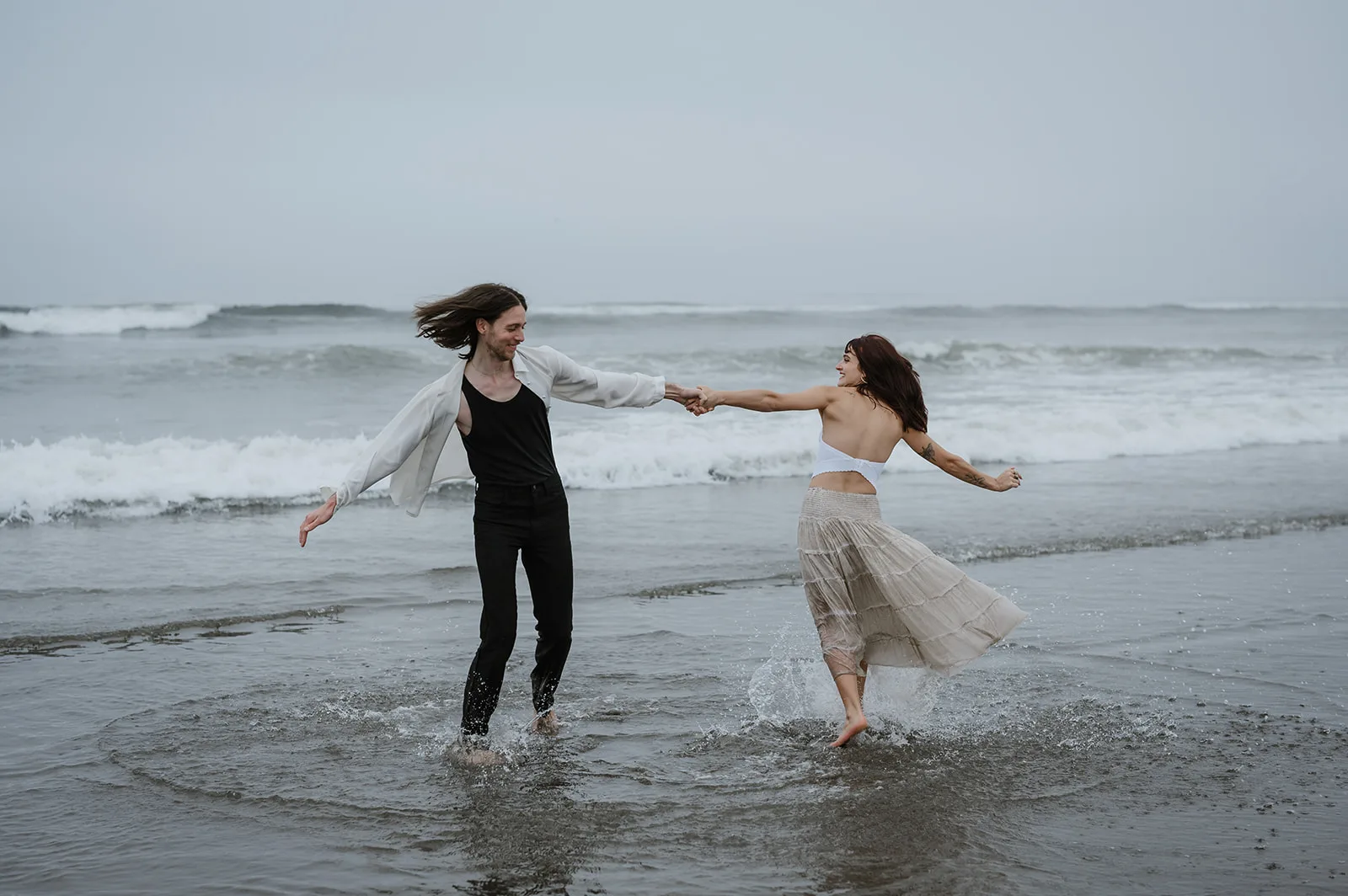 Couple joyfully running through the surf on the Oregon coast