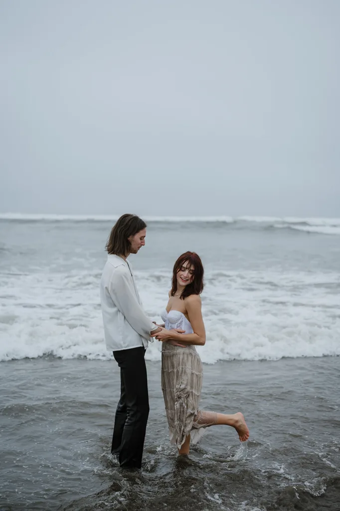 Couple standing in the surf, sharing a loving gaze on the Oregon coast