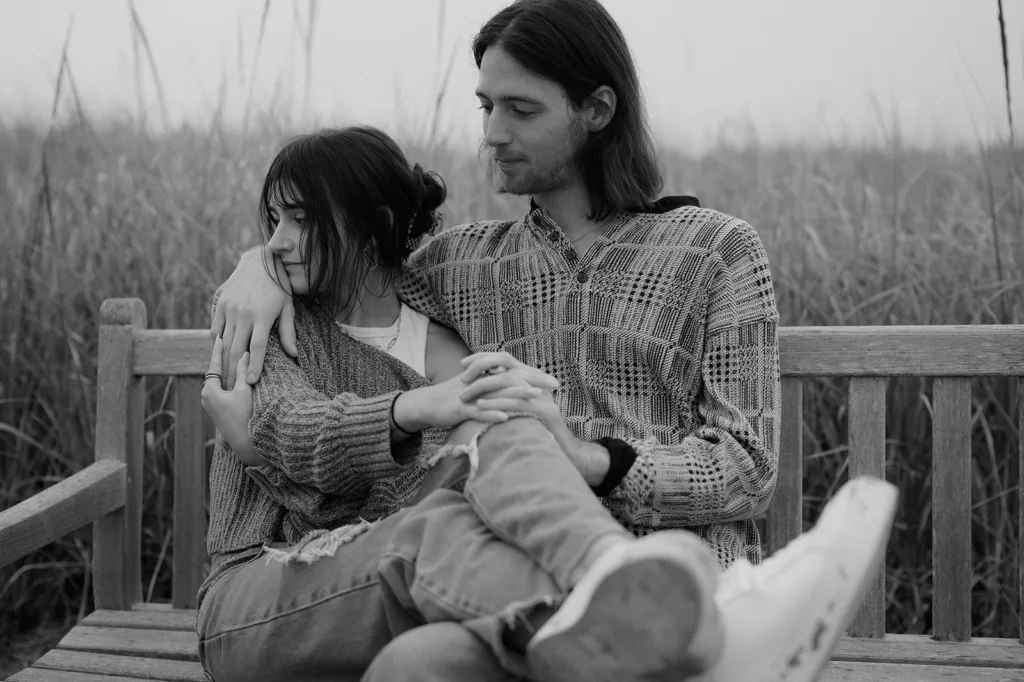 Intimate black and white engagement portrait on a wooden bench, Oregon coast