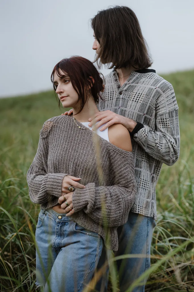 Engaged couple standing together in tall grass on the Oregon coast