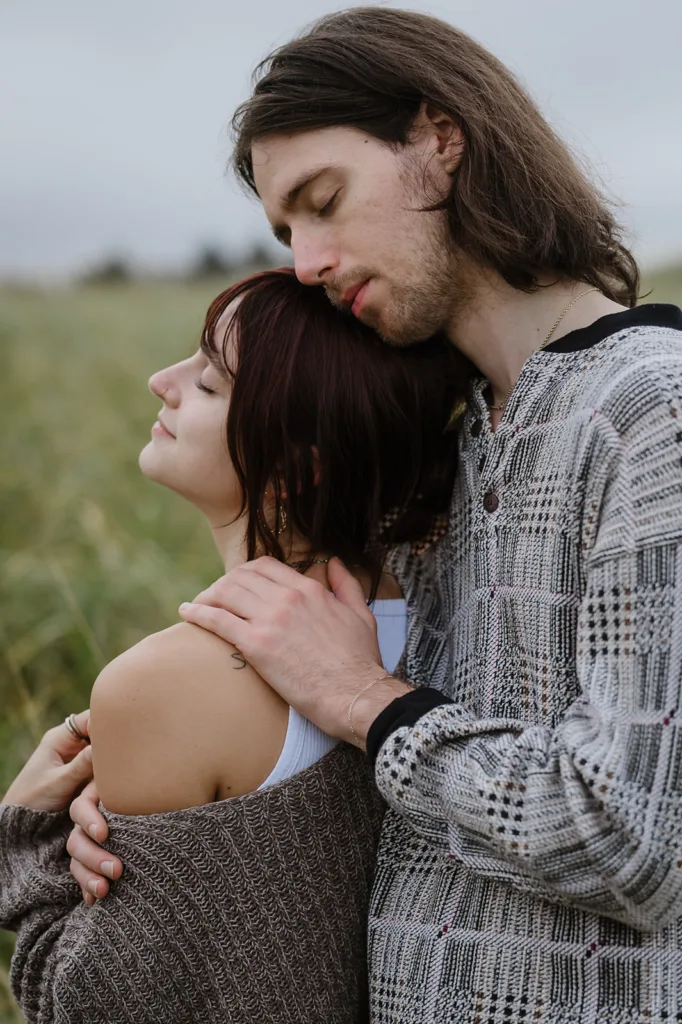 Man embracing woman from behind in a serene Oregon coast engagement photo