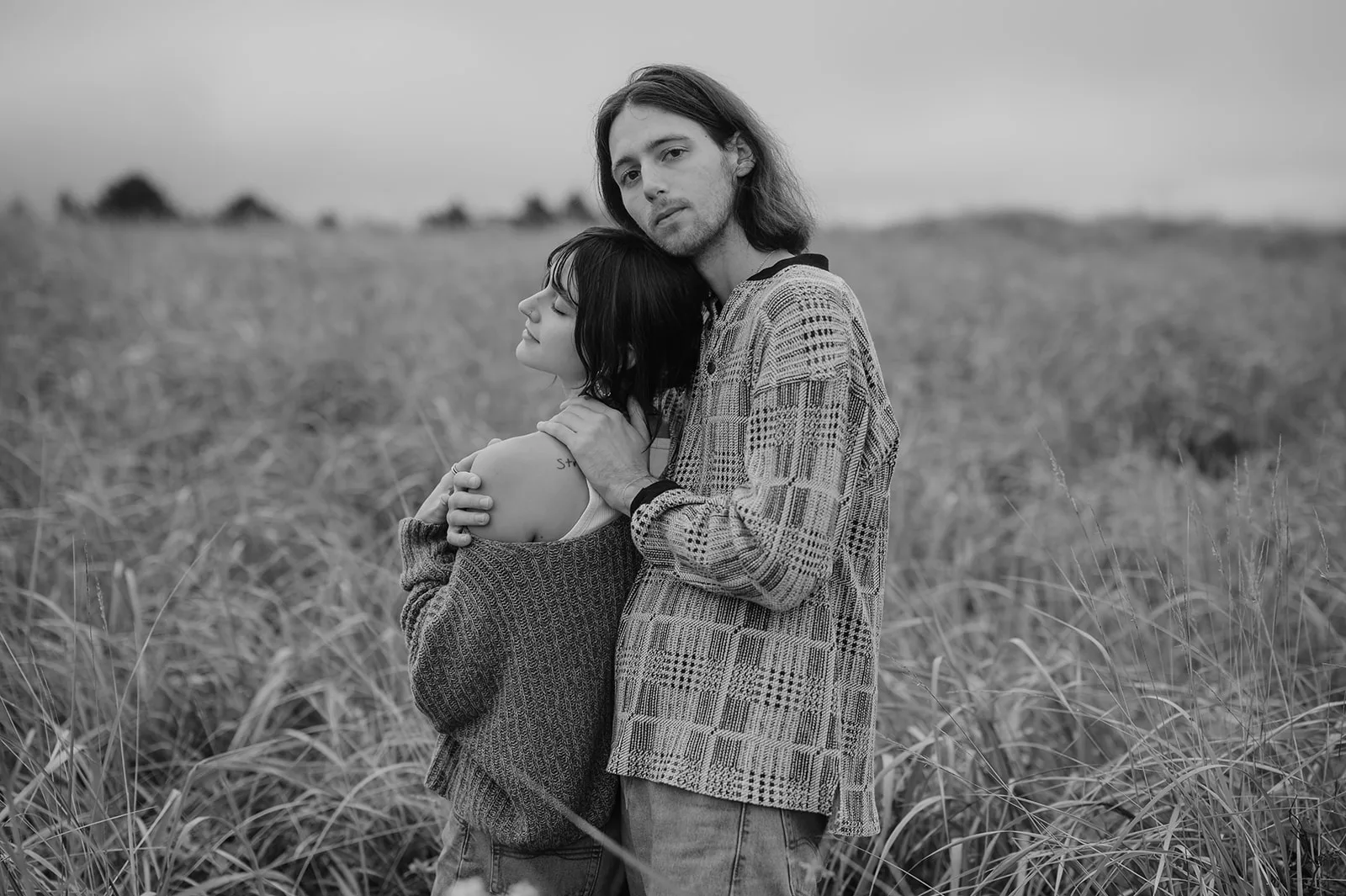 Man embracing woman from behind in a serene Oregon coast engagement photo