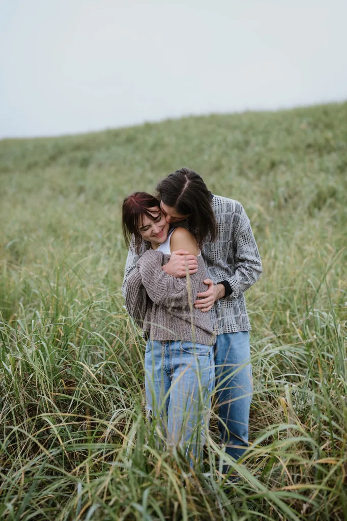 Couple sharing a close and joyous embrace in the lush fields of the Oregon coast