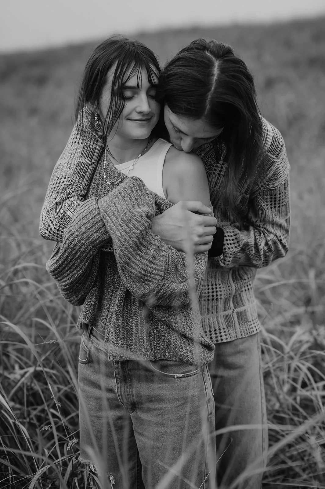 Engaged couple in a close embrace in the coastal grasses of Oregon