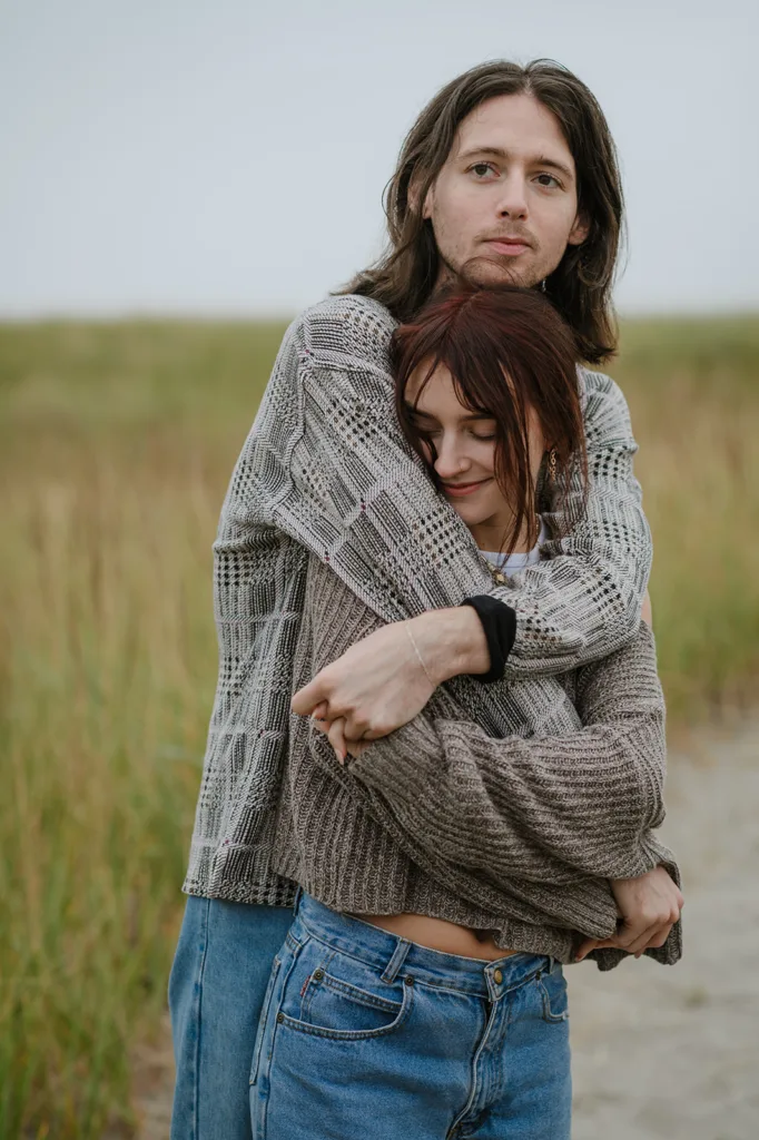 Content couple in a close hold amidst the grassy dunes of the Oregon coast