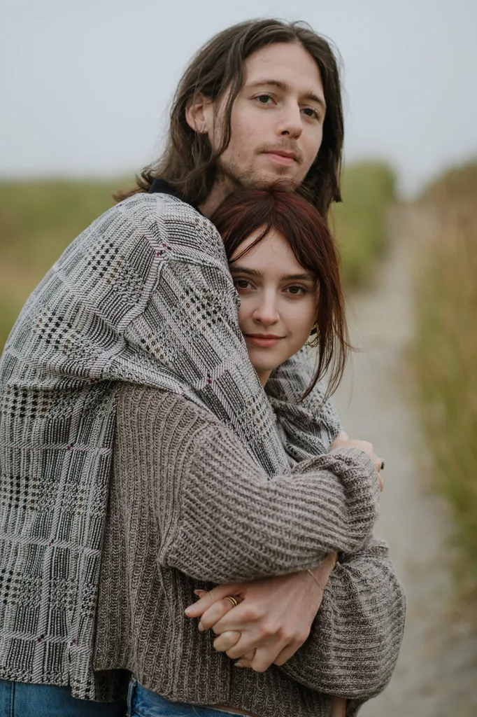Couple wrapped in a cozy embrace on a path by the Oregon coast