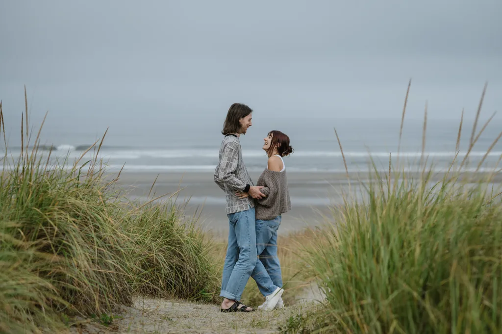 Couple standing by the beach grass with ocean waves in the background on the Oregon coast