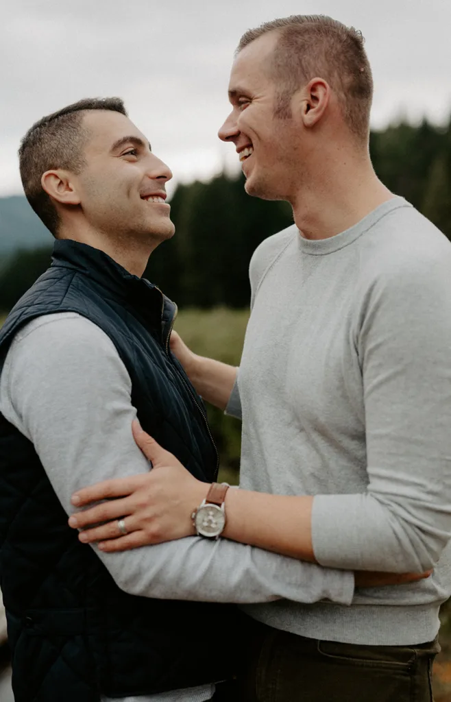 Two men sharing a close embrace, looking into each other's eyes with smiles.