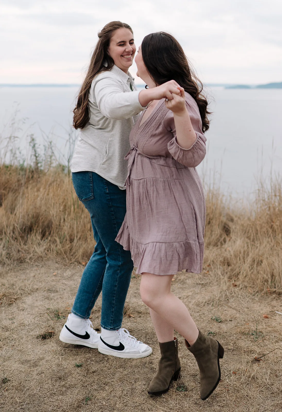 Couple dancing on a grassy hill at Discovery Park with Puget Sound in the background.