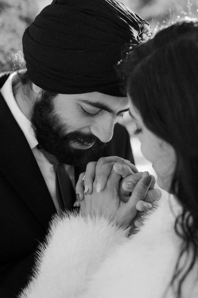 A groom whispers to his bride, holding hands tenderly, in a heartfelt moment.