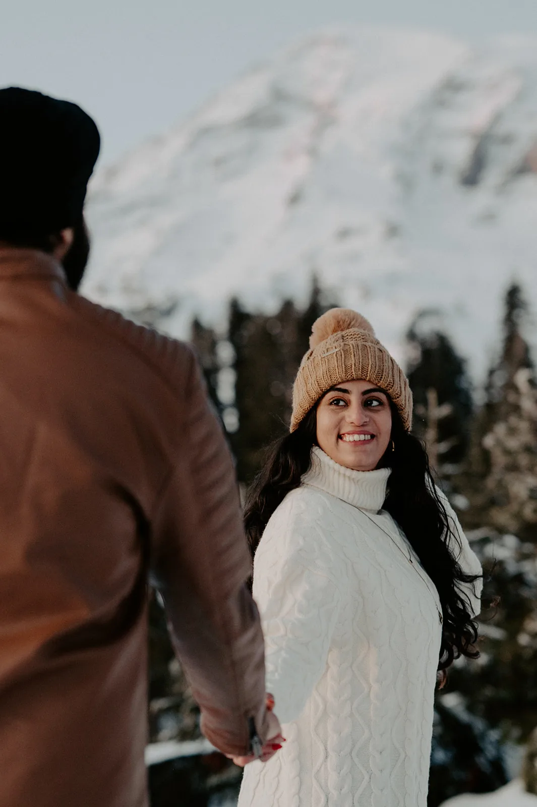 Bride looking back smiling at her partner during a snowy Mount Rainier engagement session