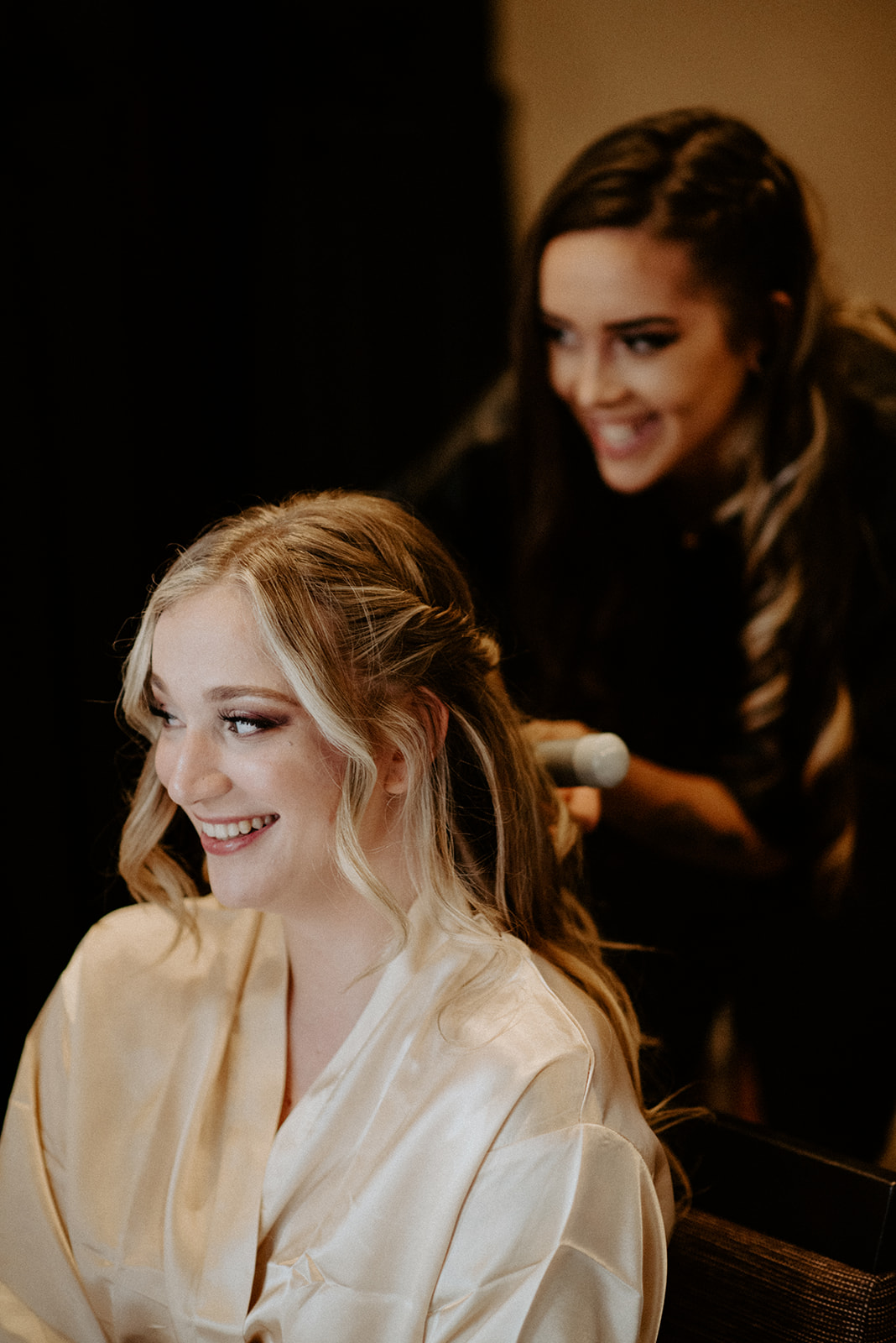 Bride smiling warmly while her hair is styled during getting-ready preparations on her wedding morning