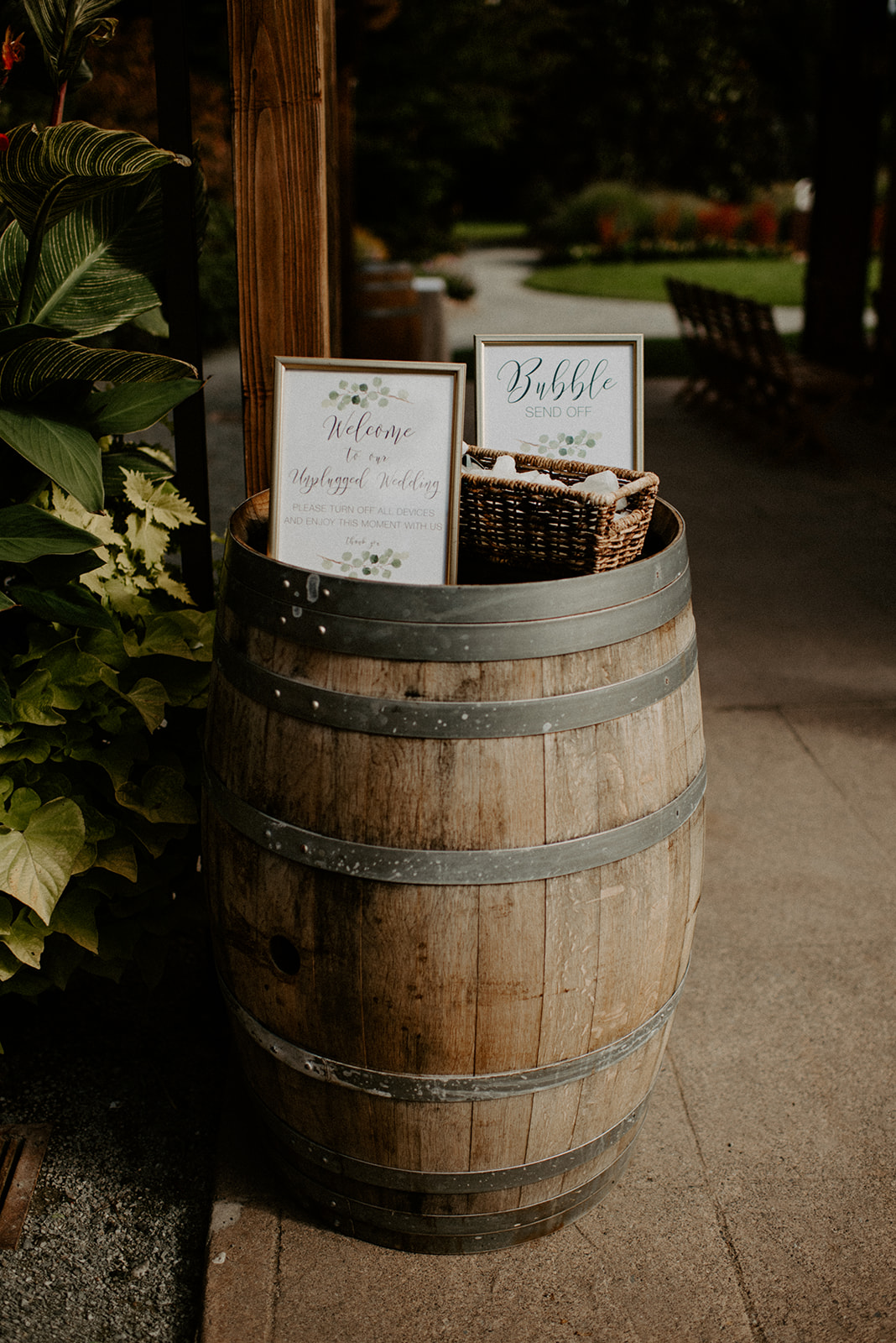 Wedding welcome sign and bubble station card displayed on a wine barrel at the ceremony entrance at Willows Lodge