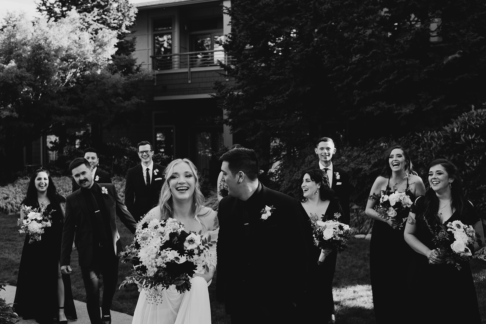Black and white photo of the full wedding party walking together along a garden path at Willows Lodge