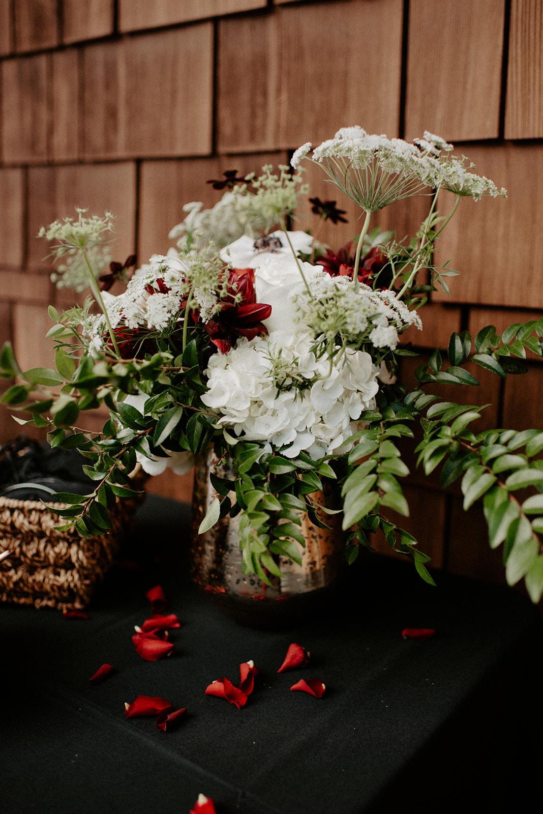 Rich reception table floral arrangement featuring deep burgundy and white blooms with lush greenery