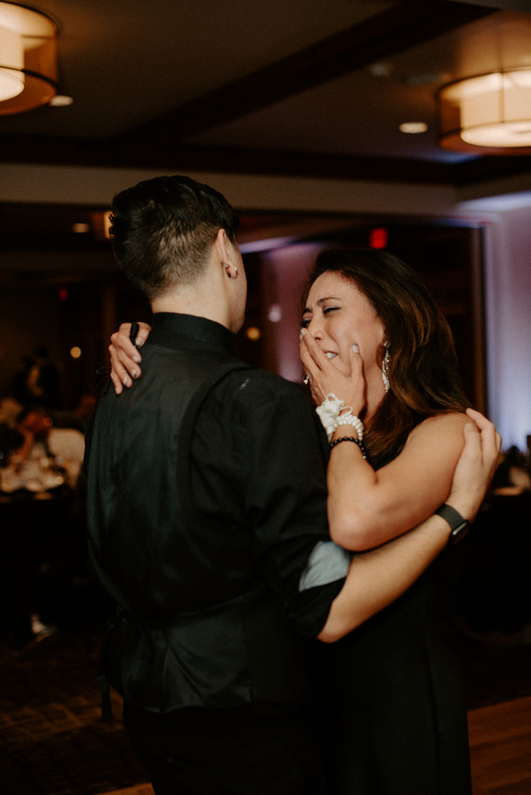 Groom dancing with his mother during the mother-son dance, she covers her mouth overcome with emotion