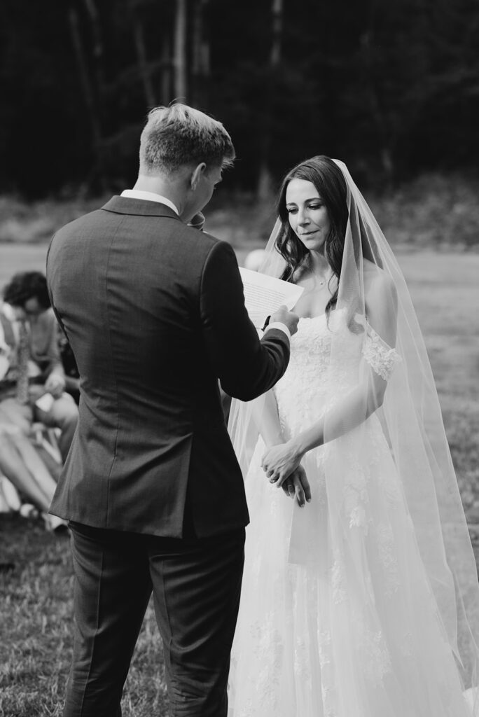Black and white photo of a groom reading personalized vows to his bride during a meaningful wedding ceremony