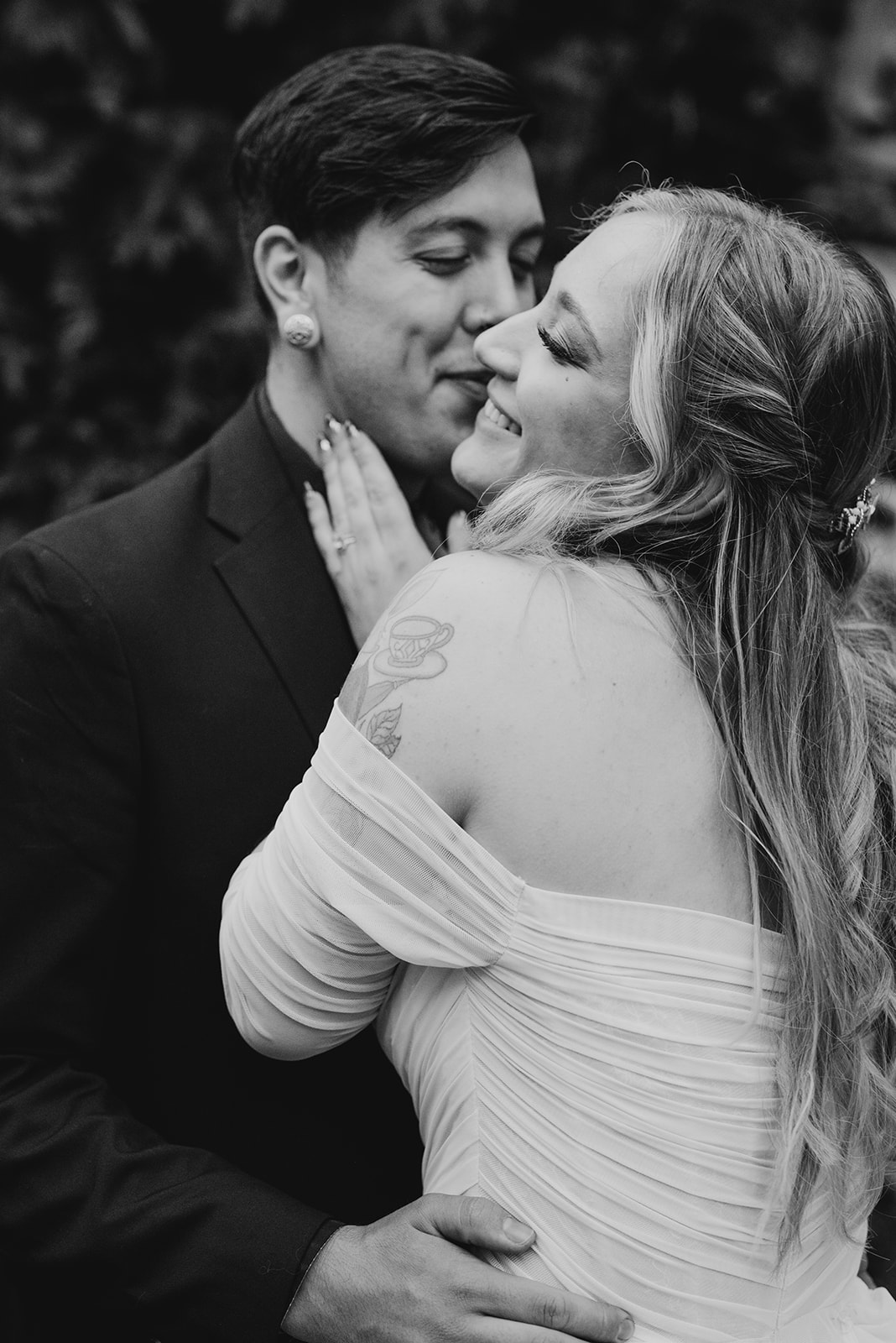 Black and white close portrait of a couple almost kissing, her hand cradling his face