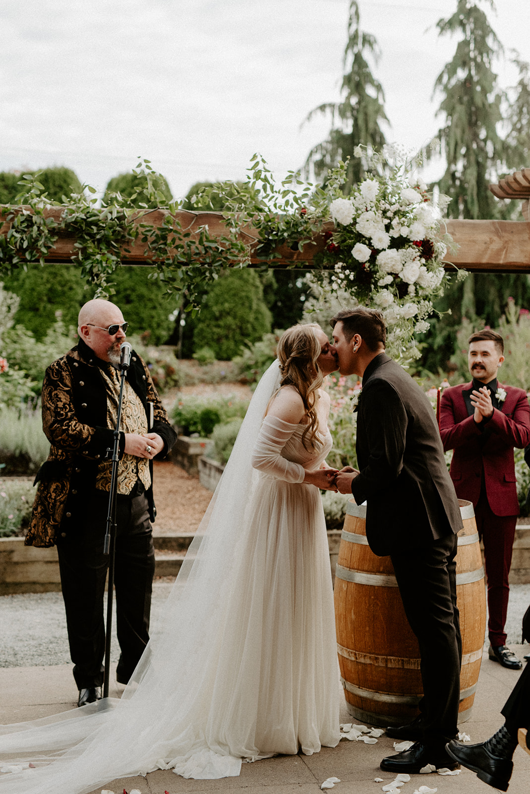 Bride and groom sharing their first kiss as a married couple at the altar at Willows Lodge, officiant and garden visible behind them