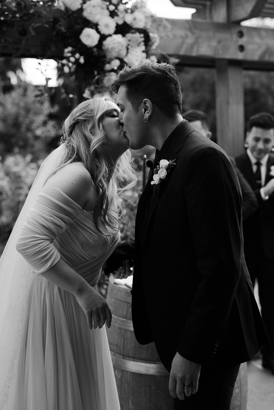 Black and white close-up of a bride and groom sharing their first kiss at the altar