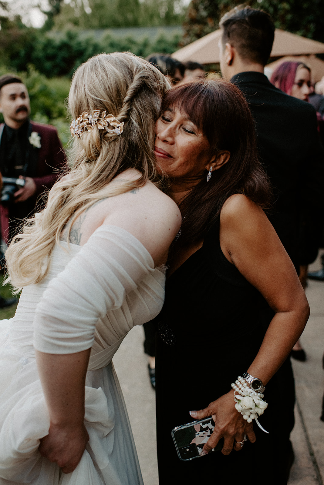 Bride being warmly embraced and kissed by a family member during cocktail hour after the ceremony