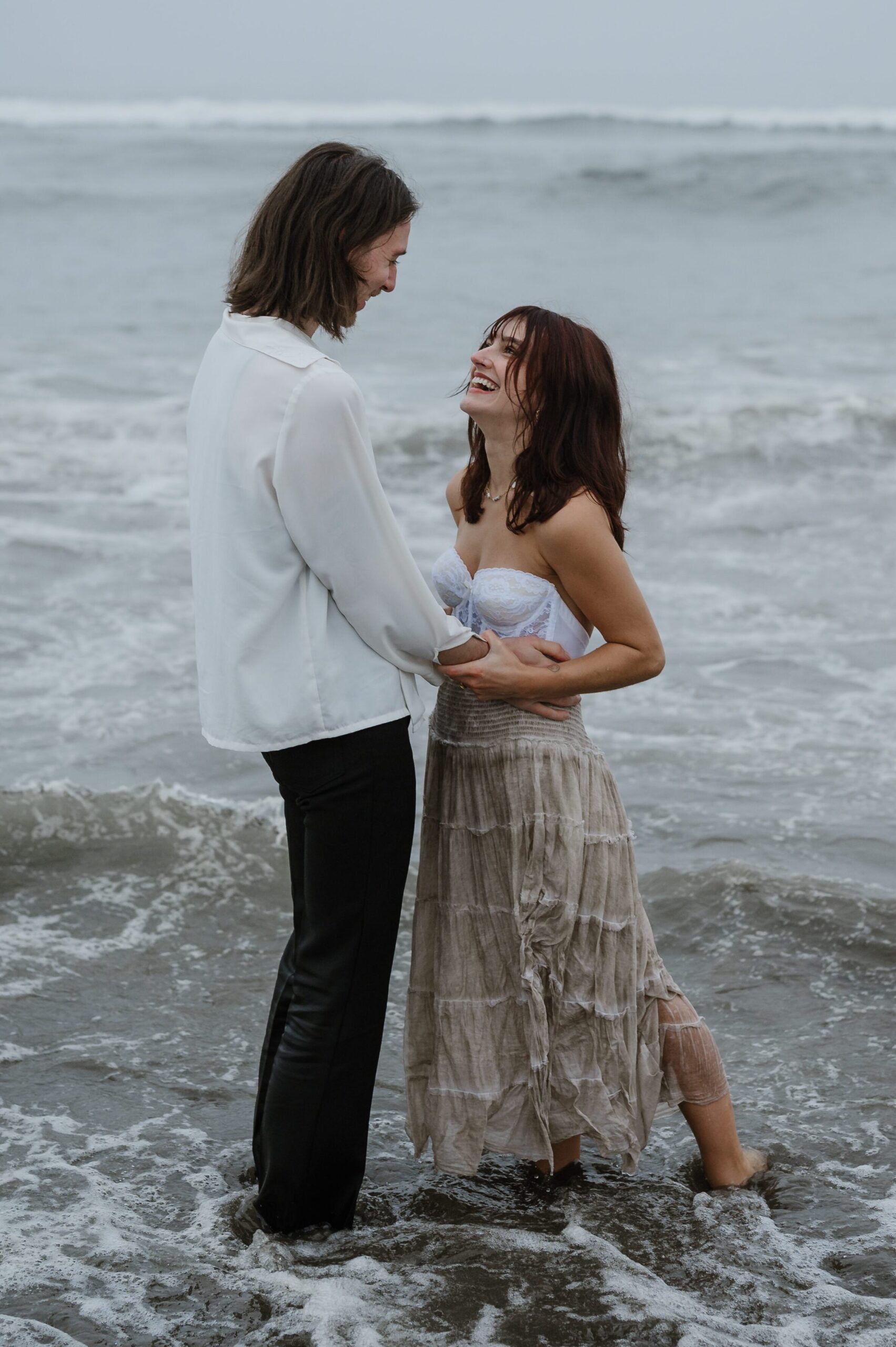 A couple sharing a joyful moment standing in the ocean waves.
