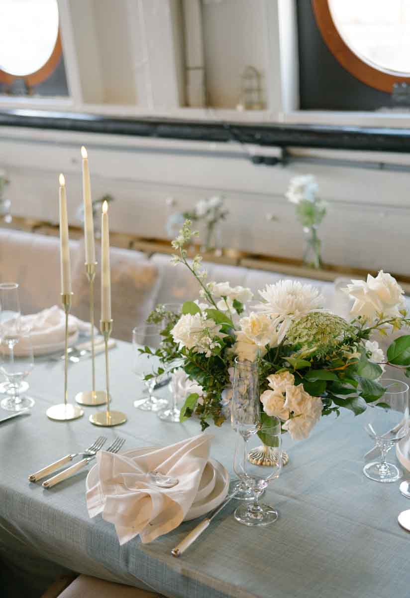 Long banquet table with elegant place settings, floral arrangements, and candles on MV Skansonia in Seattle, highlighting the venue's maritime charm and sophisticated décor.