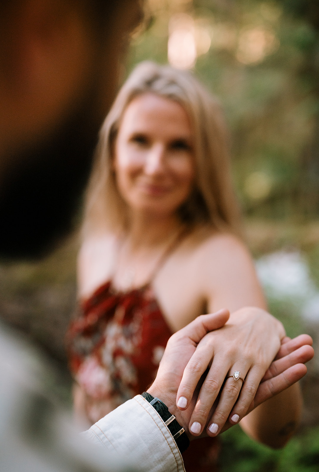 R holding M’s hand, showing off her engagement ring.