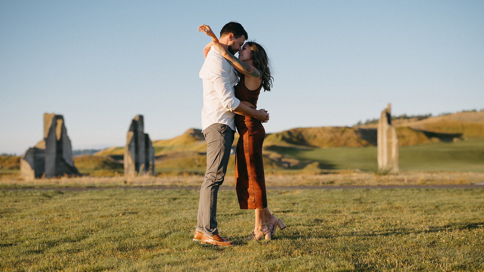 A couple embracing and smiling in an open field at Chambers Bay.