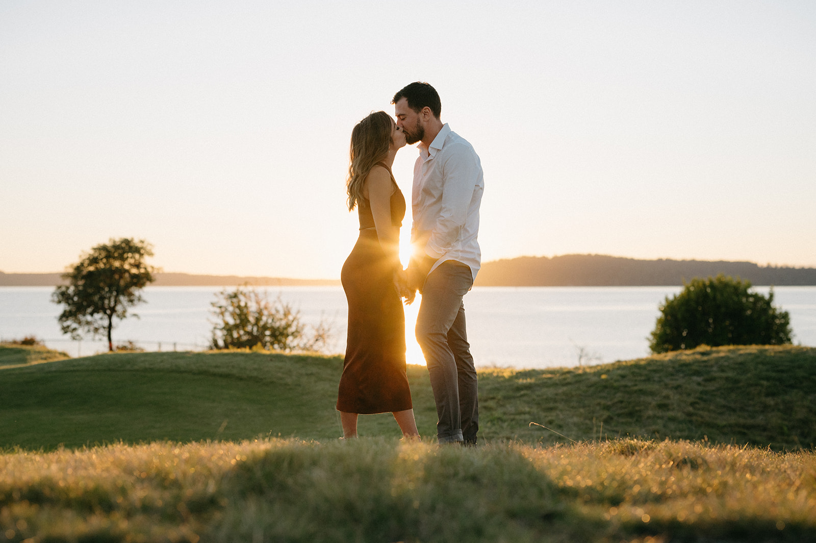 A couple kissing with the sun setting behind them at Chambers Bay.