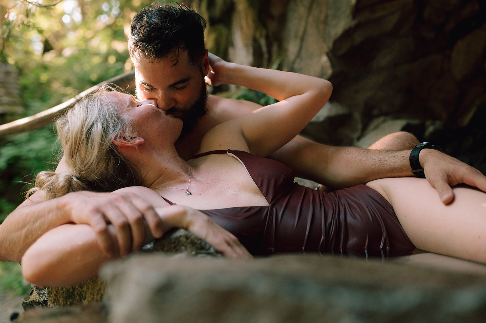 R and M sharing a kiss while lying down in a hot spring.