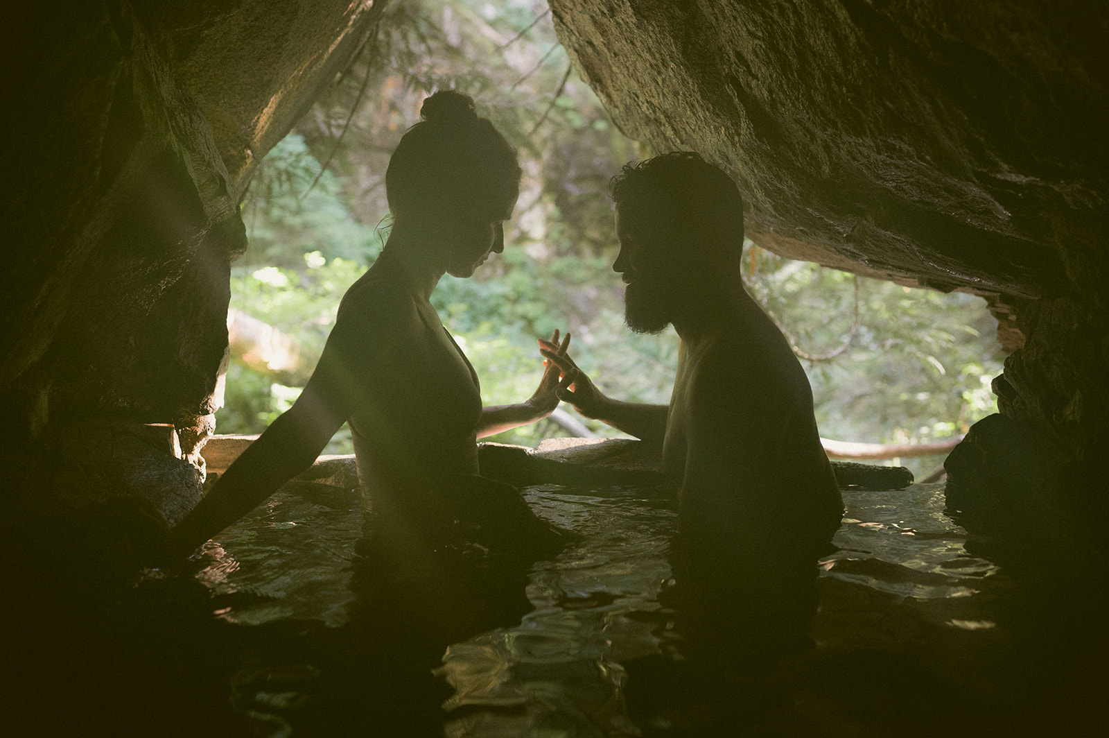 Silhouette of R and M sharing a moment in a cave hot spring.